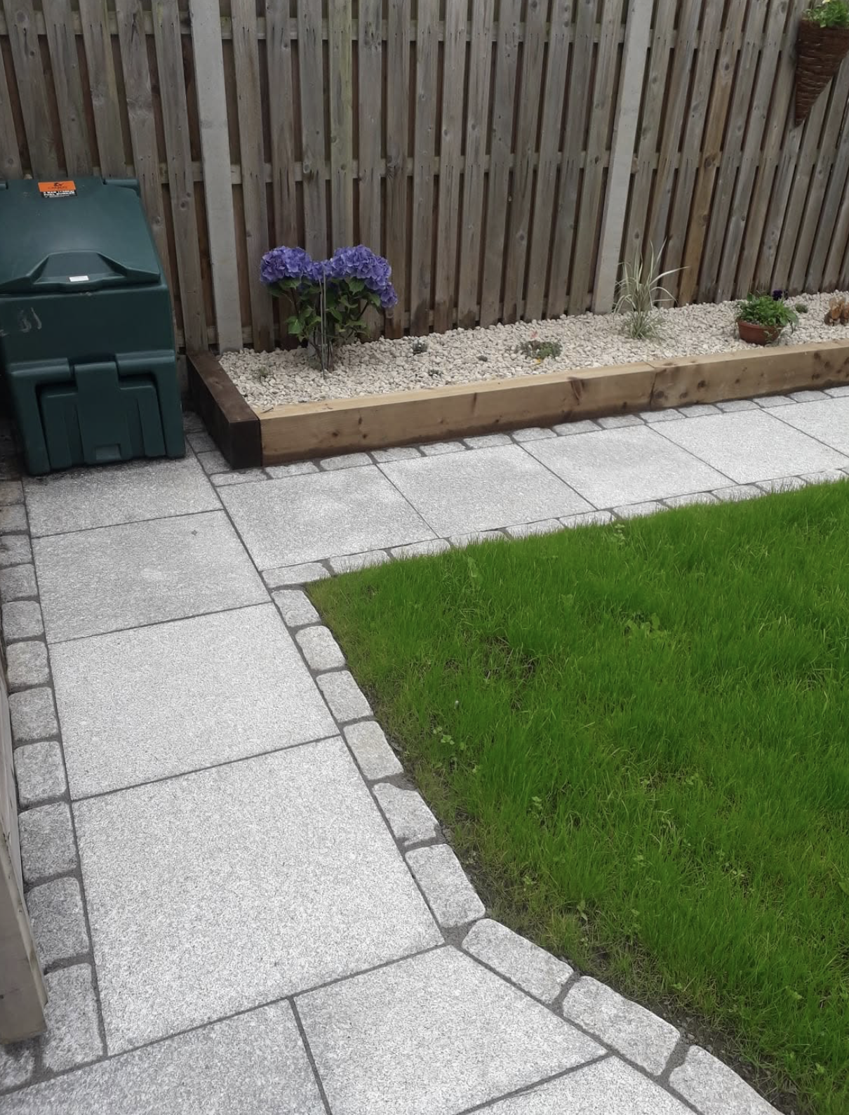 Silver granite paved path with cobble edging meeting a fresh lawn