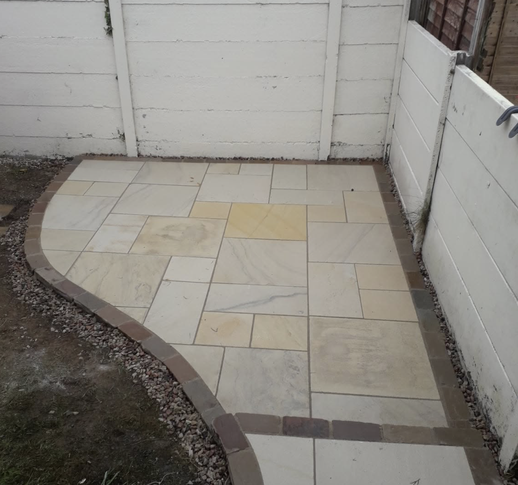 Indian sandstone patio with brick border and curved edge